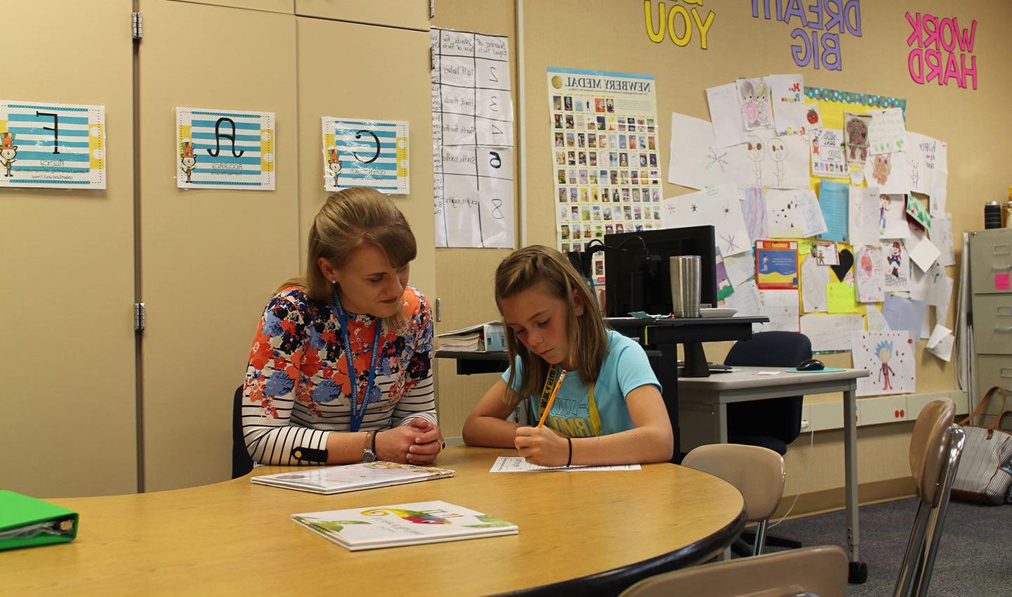 SMWC student in an elementary classroom helping a student